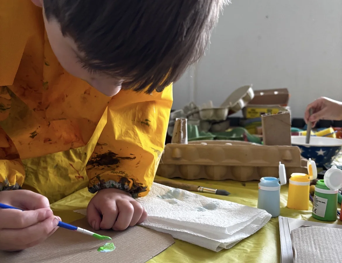 A young Creator painting a handmade piece as part of a creative tabletop activity