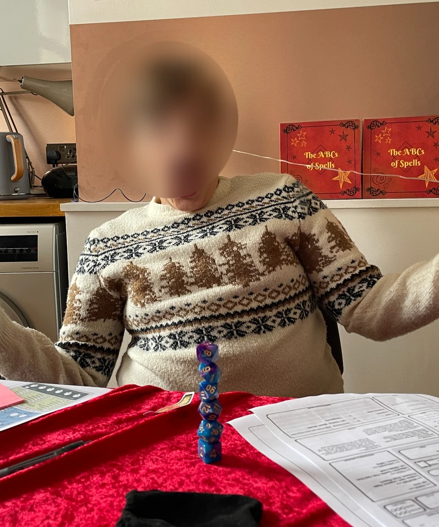 A young participant balancing a tower of dice at the table, with their face tightly anonymised for privacy